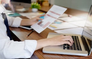 Closes-up young businessman using a laptop in a modern office