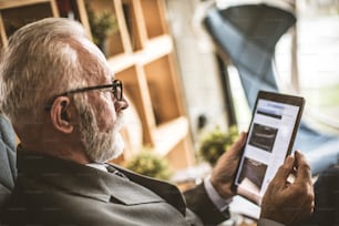 Senior businessman working on his digital tablet. Close up.