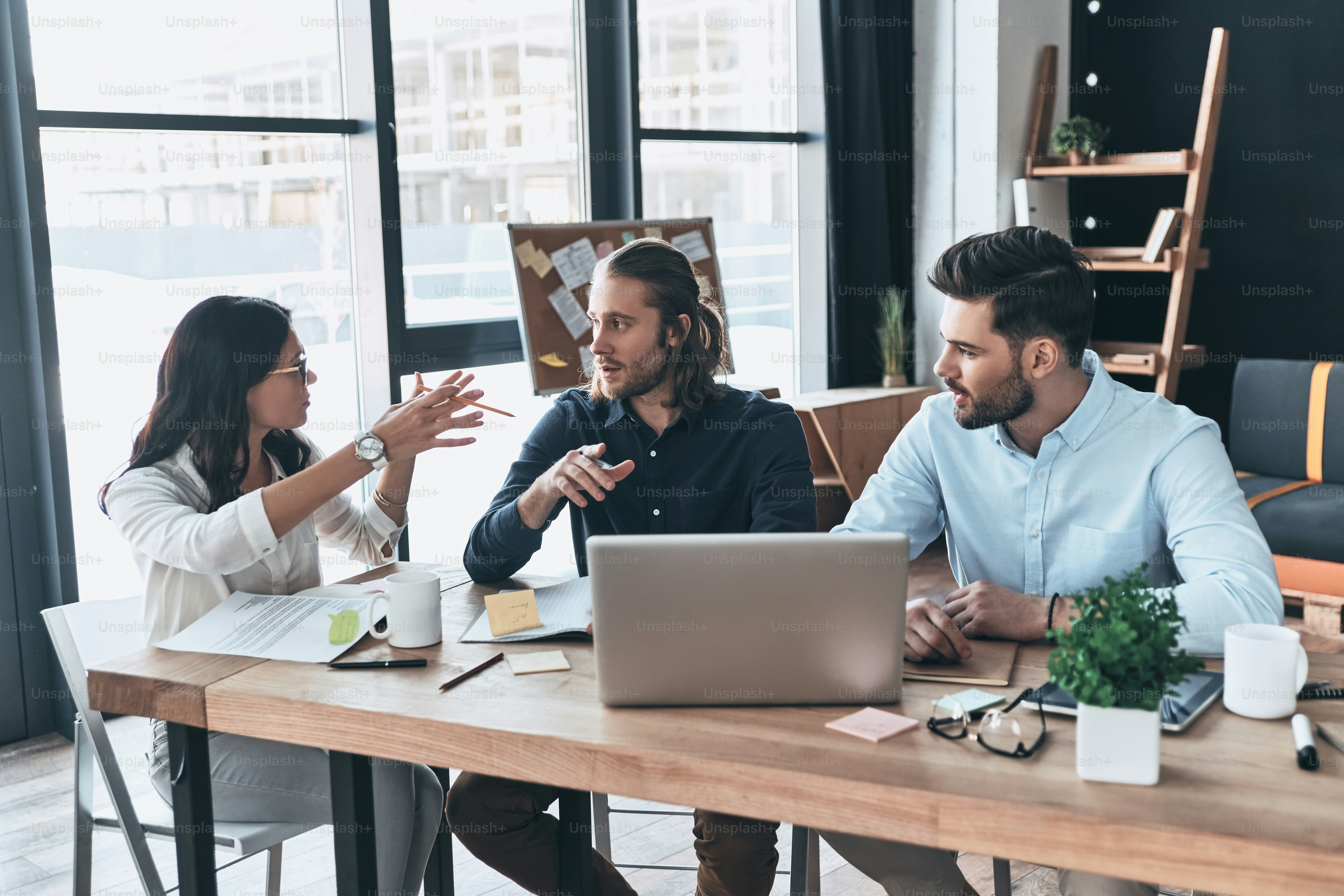 Group of young modern people in smart casual wear working together while sitting in the office