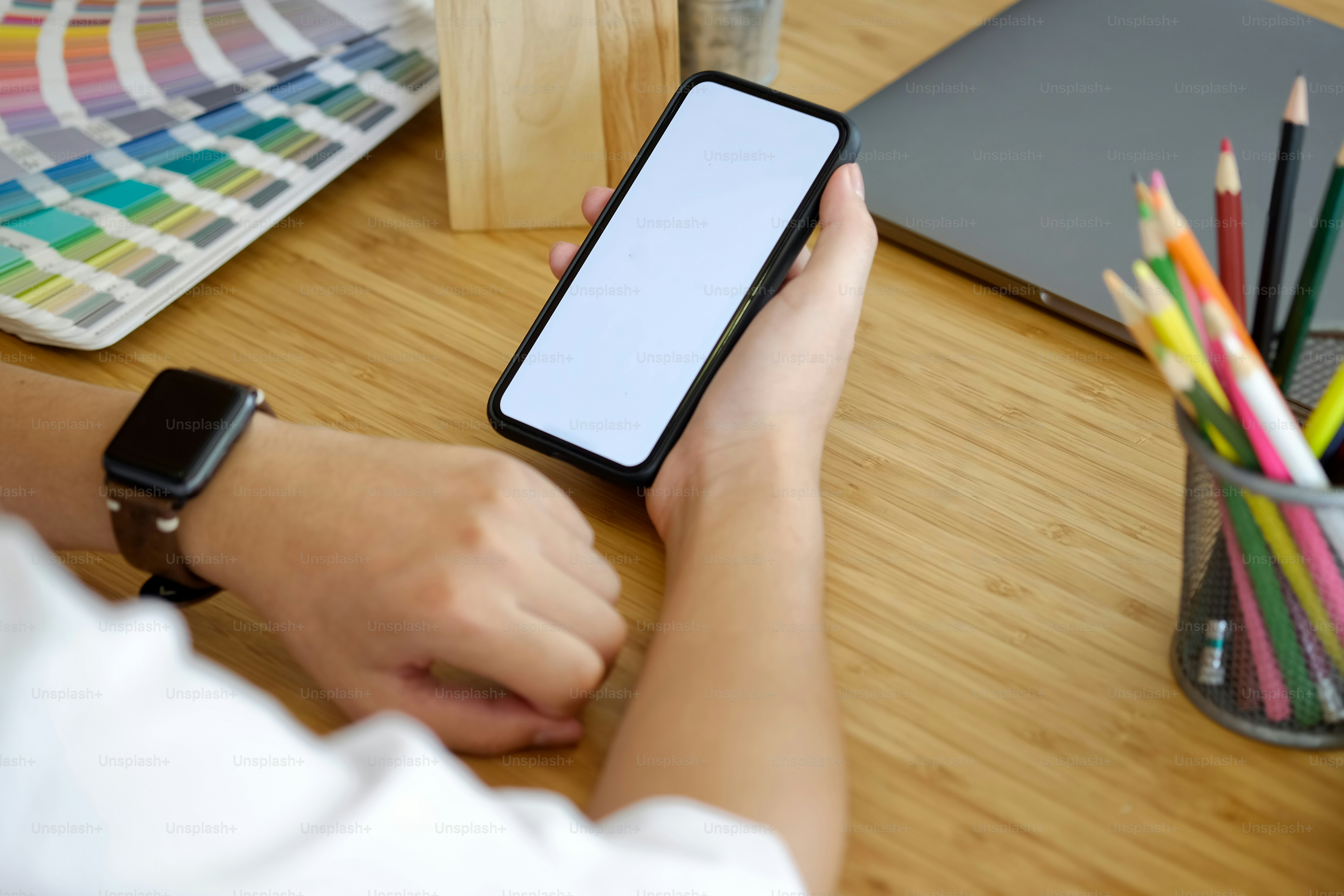 나무 책상에 스마트 시계를 연결하는 동안 스마트폰을 들고 있는 남자