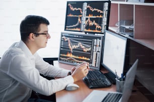 Busy working day. Close-up of young businessman looking at monitor while sitting at the desk in creative office.