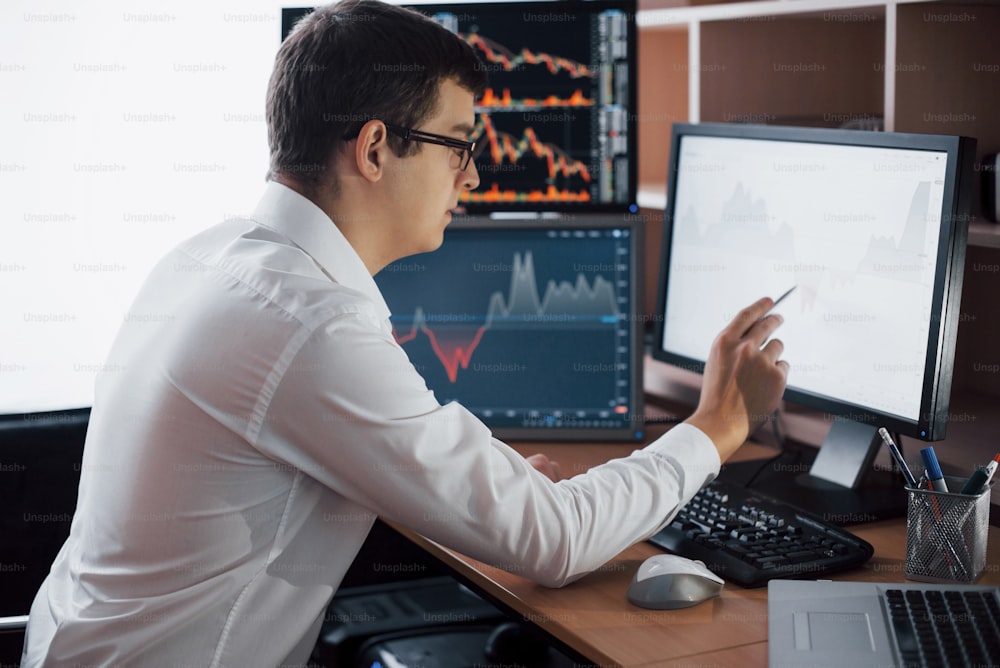 Geschäftiger Arbeitstag. Nahaufnahme eines jungen Geschäftsmannes, der auf den Monitor schaut, während er am Schreibtisch im Kreativbüro sitzt.