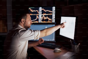 Stockbroker in shirt is working in a monitoring room with display screens. Stock Exchange Trading Forex Finance Graphic Concept. Businessmen trading stocks online.