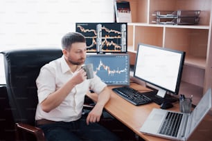 Stockbroker in shirt is working in a monitoring room with display screens. Stock Exchange Trading Forex Finance Graphic Concept. Businessmen trading stocks online.