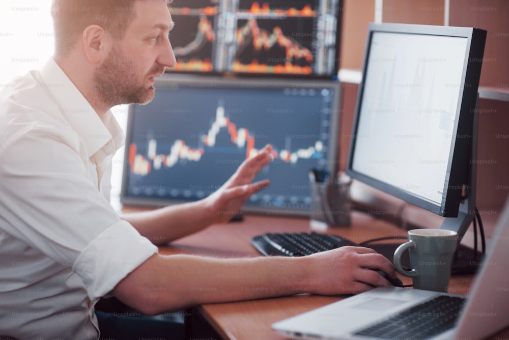 Stockbroker in shirt is working in a monitoring room with display screens. Stock Exchange Trading Forex Finance Graphic Concept. Businessmen trading stocks online.