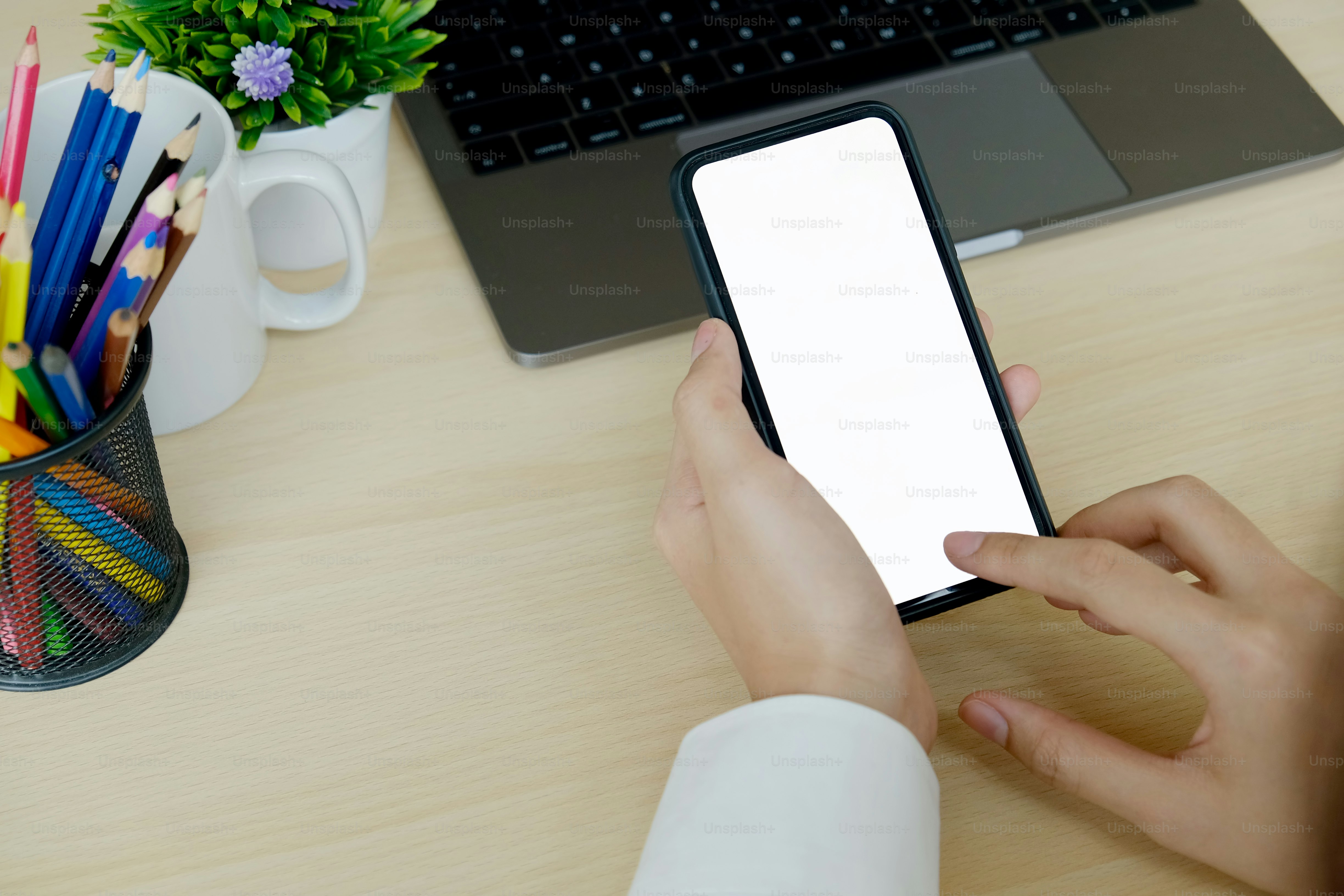 현대 사무실에서 나무 책상에 빈 화면 스마트폰을 들고 있는 사업가