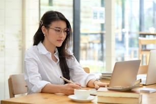 Foto de uma jovem empresária asiática trabalhando em seu laptop no escritório.