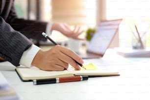 Businessman analysis data in computer and short note on sticky note paper side view on table office.