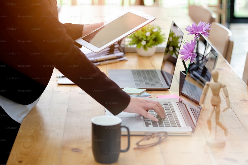 Young attractive businesswoman working on a laptop and tablet in her office