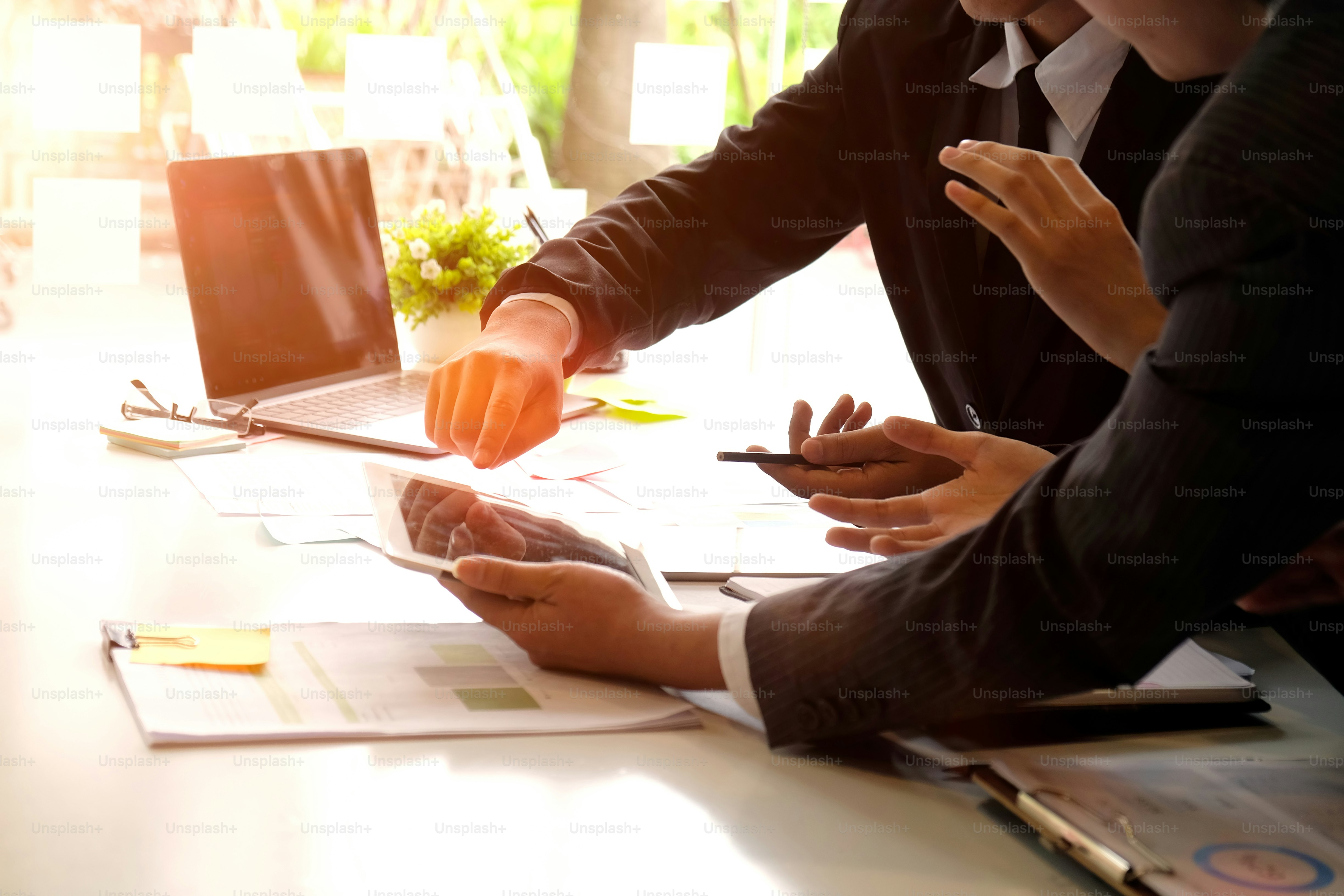 Gruppe von Geschäftsleuten, die etwas auf einem Tablet und Papierkram im Sitzungssaal diskutieren.