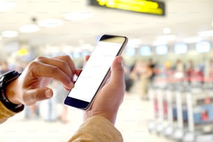 Hombre de negocios usando un teléfono inteligente en el aeropuerto". Teléfono móvil con pantalla en blanco para montaje gráfico.