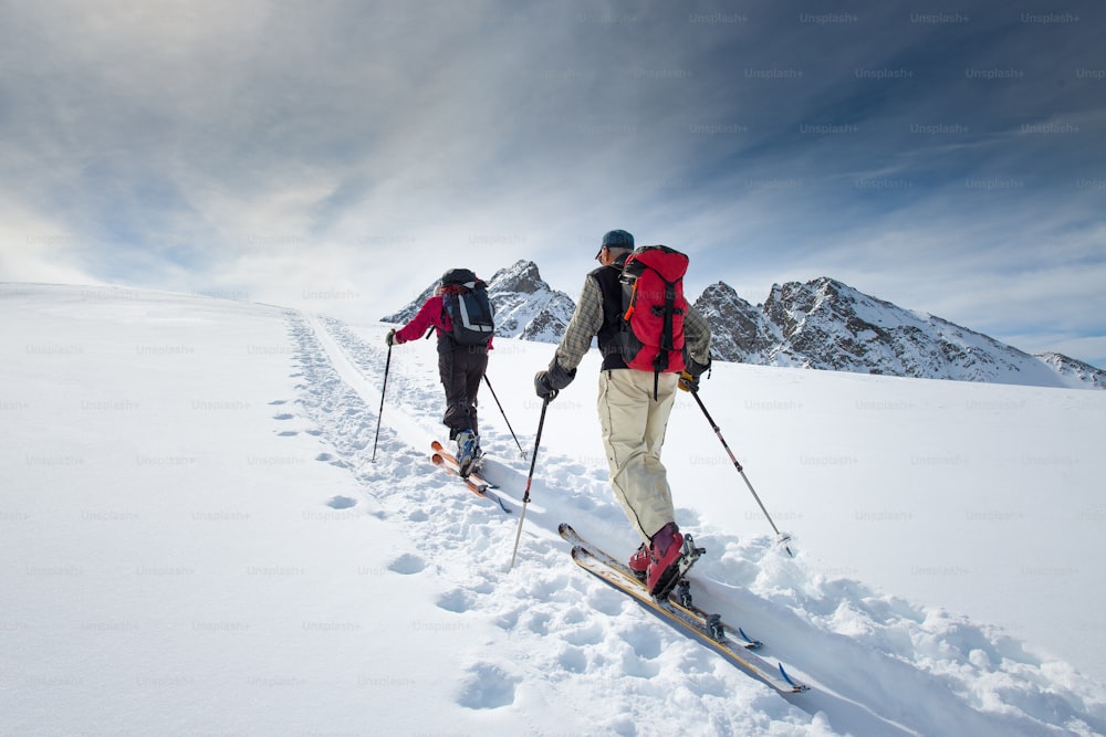 Dos esquiadores alpinos de edad avanzada se suben a esquís y pieles de foca