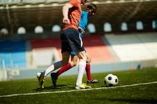 Dos futbolistas rivales siguiendo un balón de fútbol