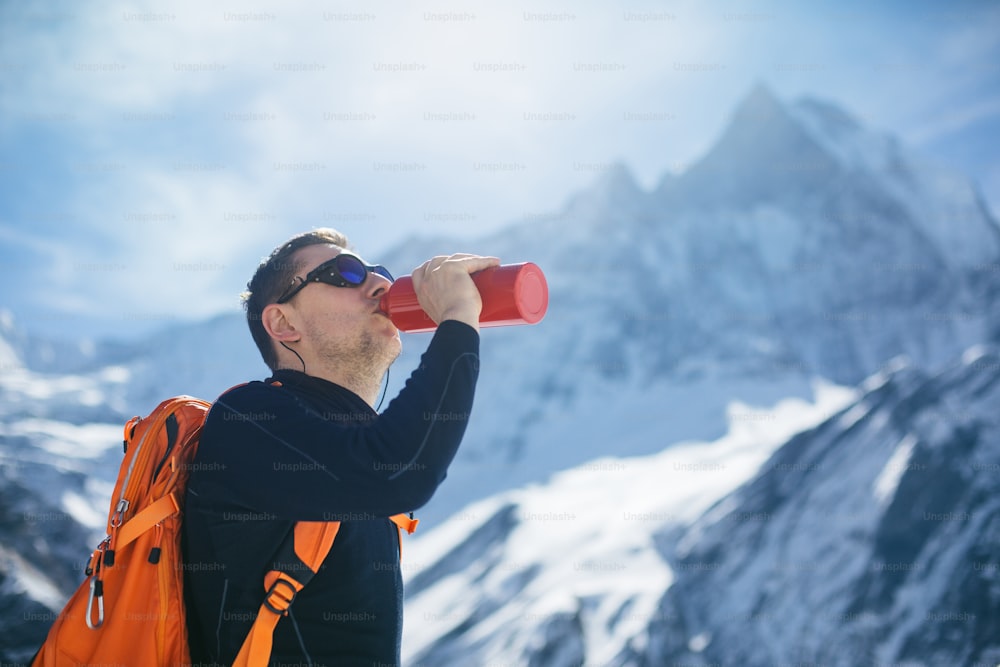 Excursionista bebiendo agua en montañas. Al fondo se encuentra el Machapuchare (6993m) también conocido como Cola de Pez, hasta el día de hoy esta cumbre no ha sido escalada.