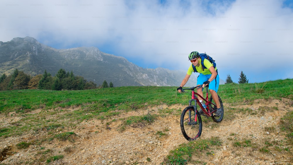 A young male riding a mountain bike outdoor in the meadow