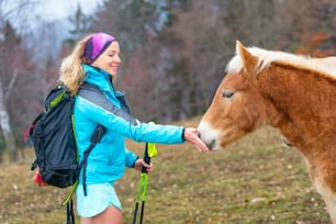 La ragazza sportiva in natura dà l'erba per mangiare un cavallo
