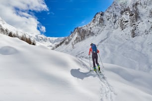 Chica hace esquí de montaña cuesta arriba sola en los Alpes
