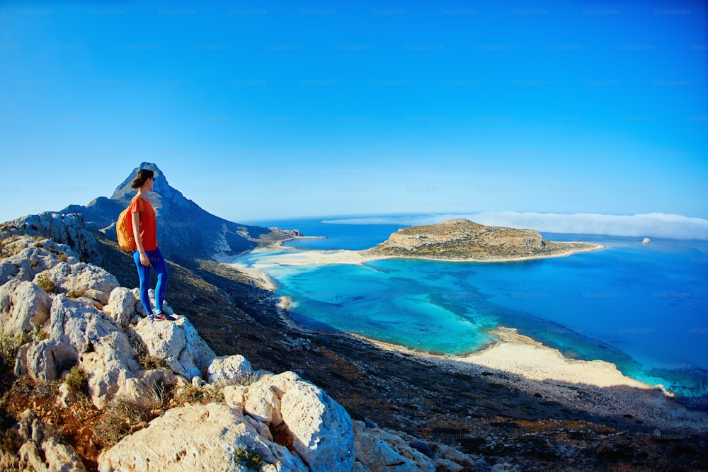 vista panoramica sulla spiaggia di Balos, Creta, Grecia. Donna, viaggiatore si leva in piedi sulla scogliera contro lo sfondo del mare