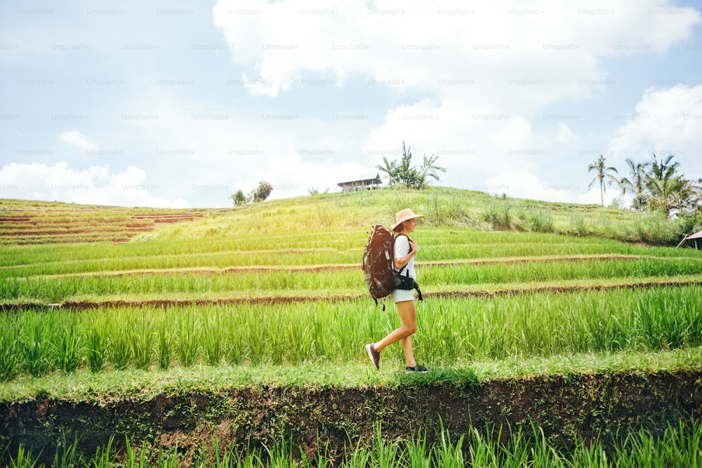 Joven viajera que camina con mochila entre terrazas de arroz