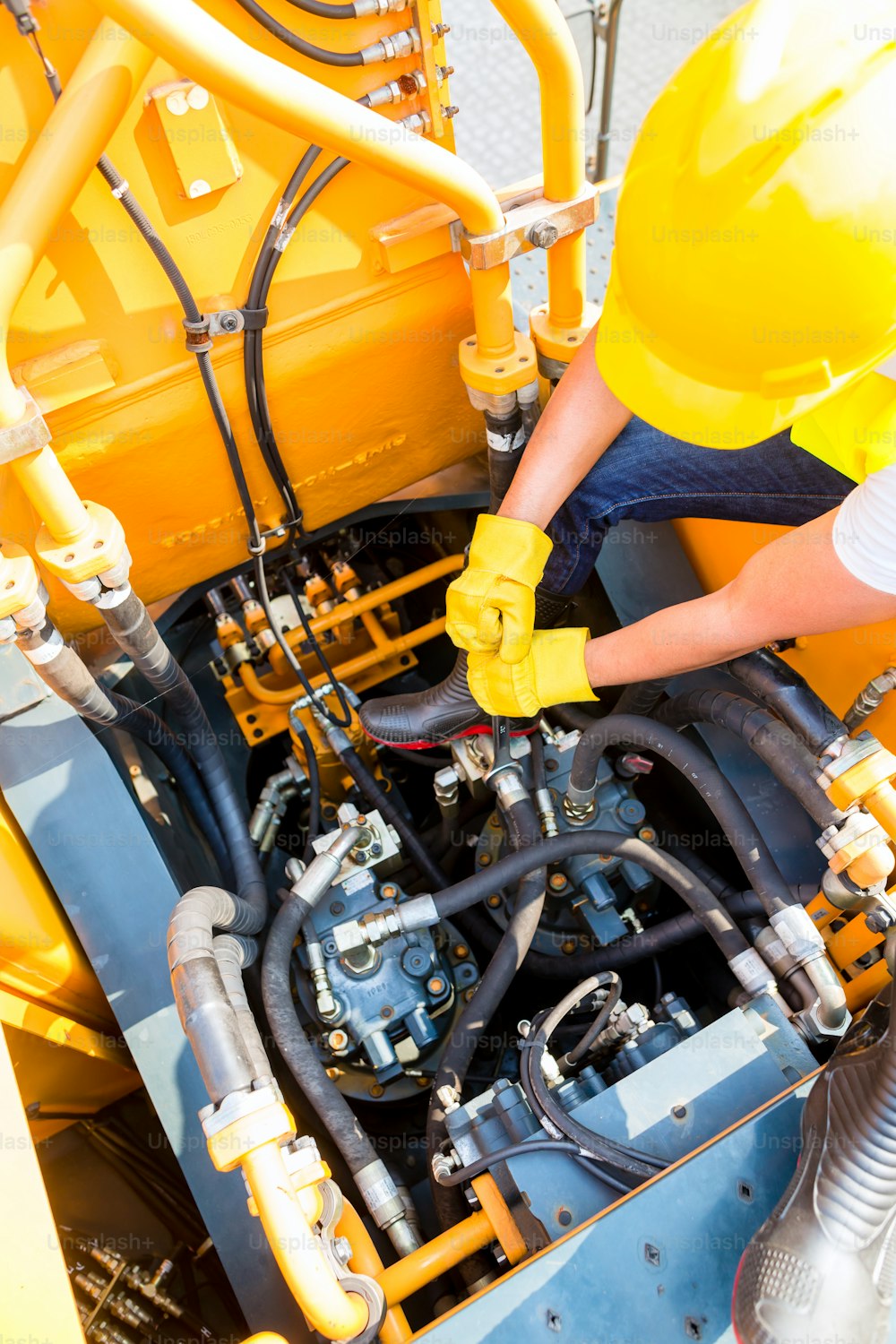 Asian motor mechanic working on construction or mining machinery in vehicle workshop