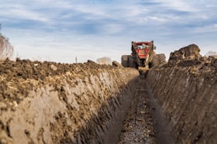 Traktor mit zweirädrigem Grabengraben, der Entwässerungskanal gräbt
