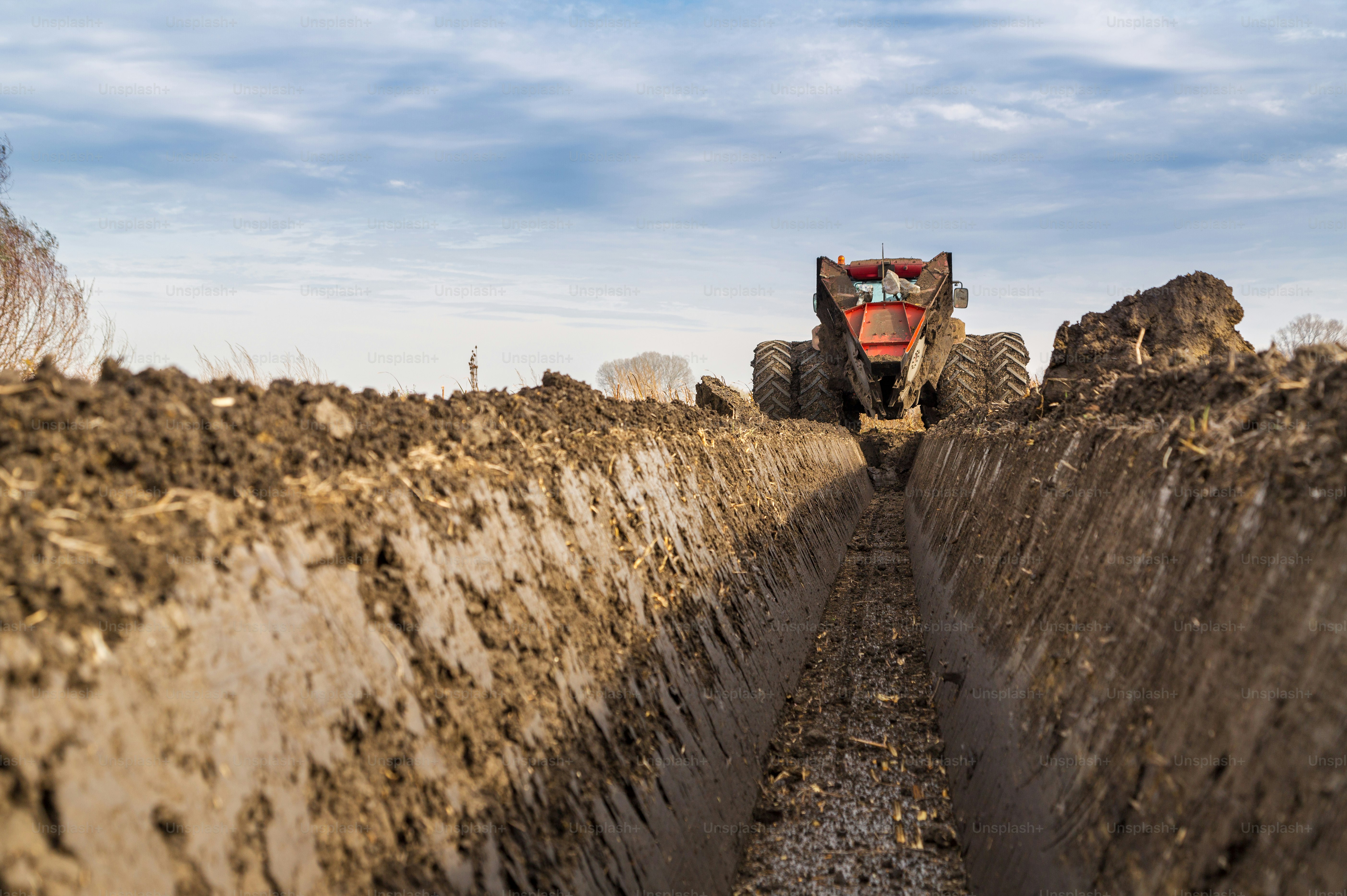 Tractor with double wheeled ditcher digging drainage canal