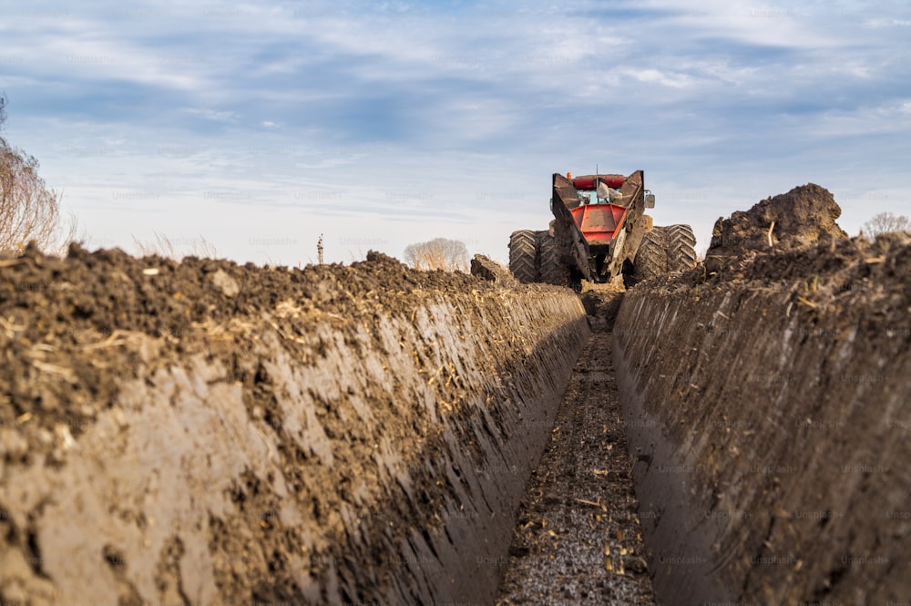 Traktor mit zweirädrigem Grabengraben, der Entwässerungskanal gräbt