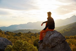 male traveler  standing on the cliff against mountains and cloudy  sky at early morning