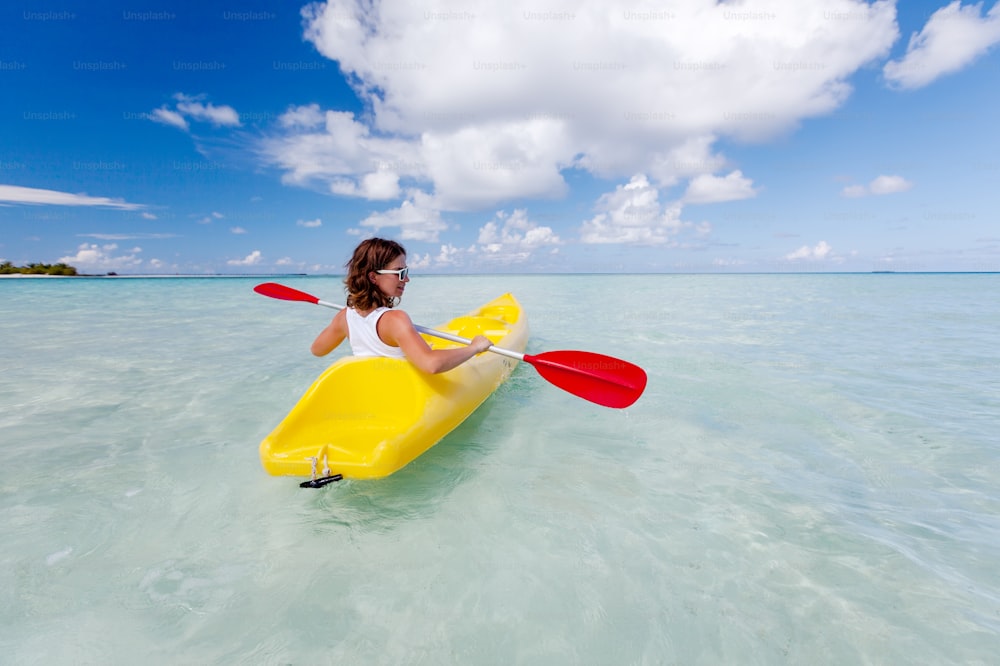 Joven mujer caucásica navegando en kayak en el mar en Maldivas