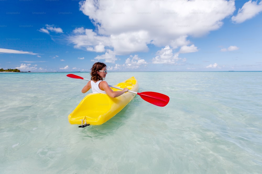 Young caucasian woman kayaking in sea at Maldives