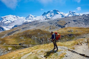escursionista stanco con zaino sul sentiero nelle montagne Apls. Trekking vicino al Monte Cervino