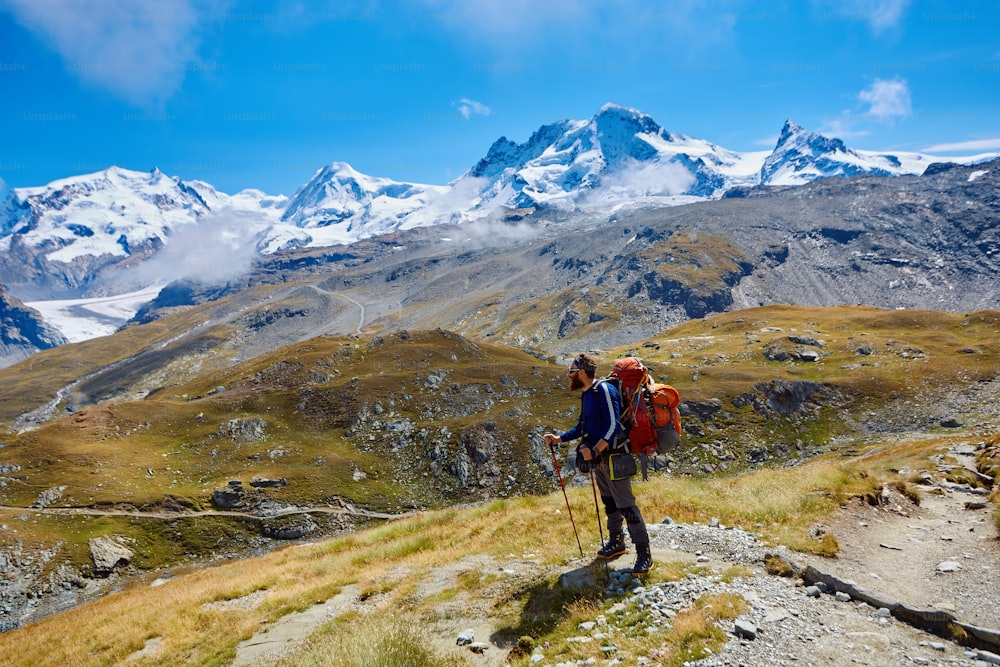 tired hiker with backpack on the trail in the Apls mountains. Trek near Matterhorn mount