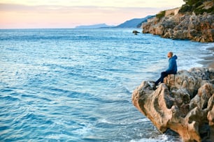 man sitting on the cliff on the beach against the sea  at early morning
