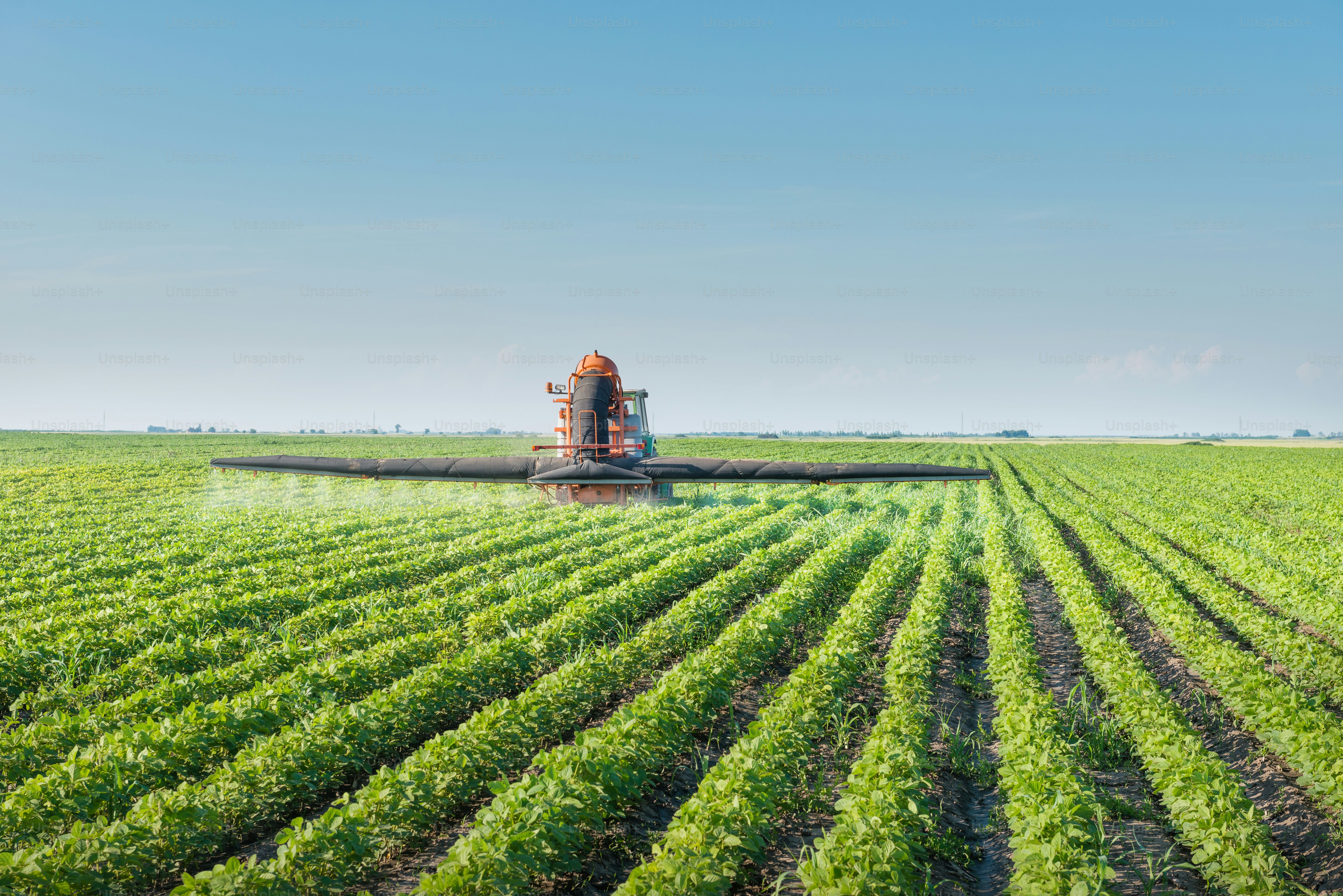 tractor spraying pesticides on soy bean