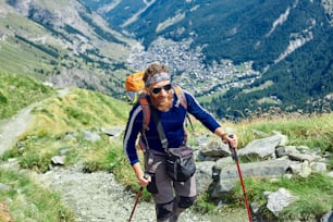 배낭을 메고 고개 꼭대기에 있는 등산객은 알프스에서 화창한 날을 즐긴다. 스위스, 마테호른 산 근처의 트레킹.