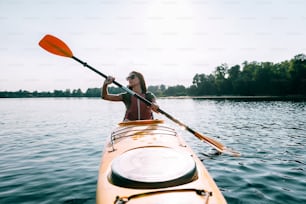 Front view of beautiful young smiling woman kayaking on lake and smiling