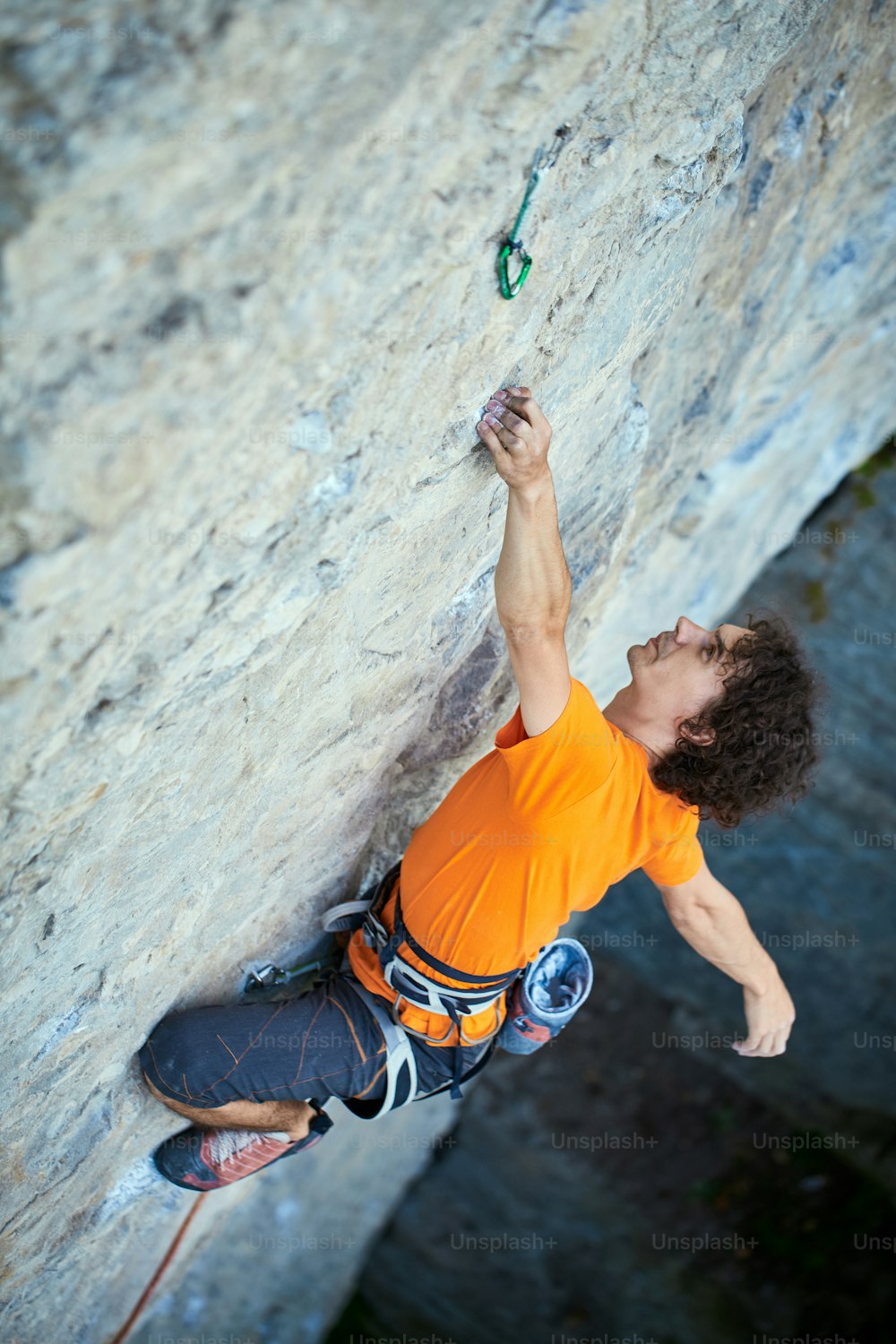 Männlicher Kletterer. Kletterer klettert auf eine Felswand. Ein Mann, der an einer Hand hängt und ruht. Fokus auf die Hand