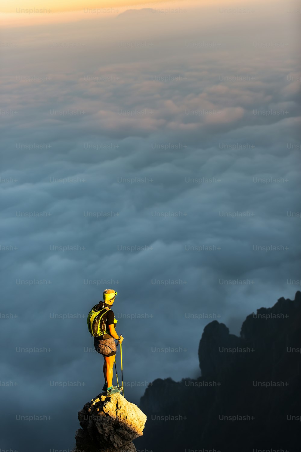 구름 바다가있는 산 첨탑 꼭대기에. 사람이 트레킹 전에 휴식을 취하고 정상에서 광경을 관찰합니다.