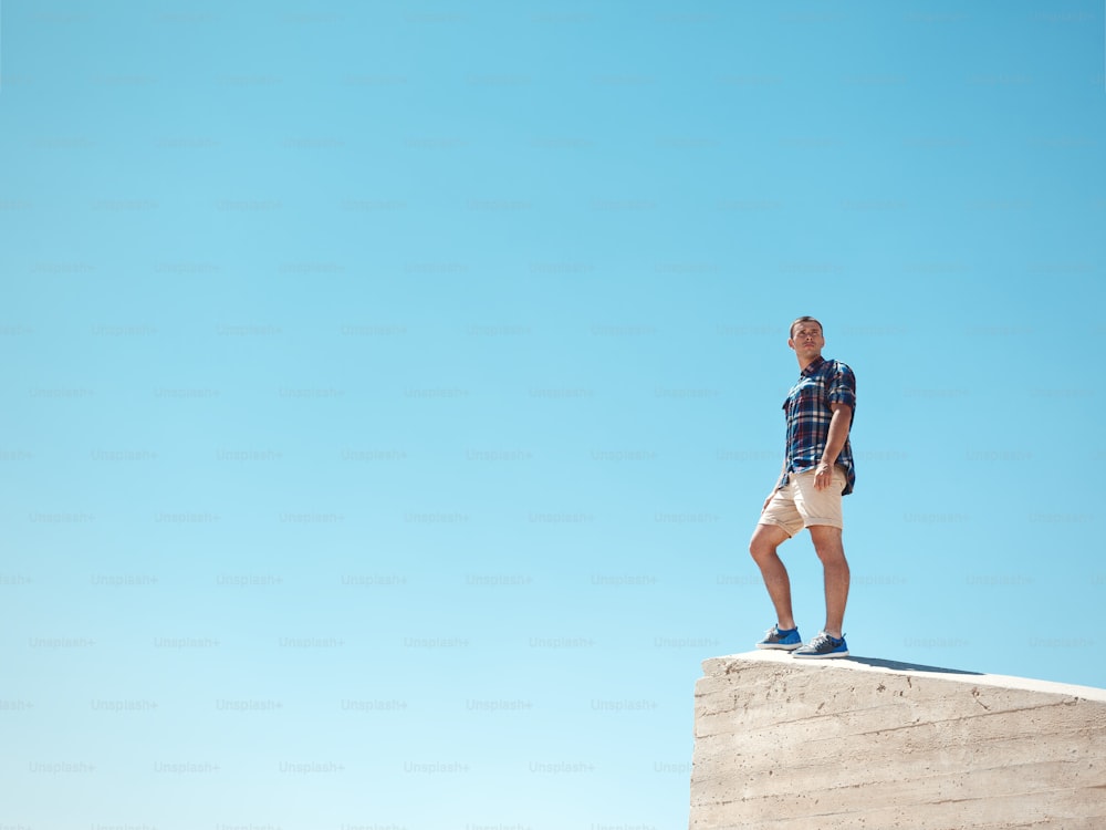 Young man standing on a peak and clear sky at the background