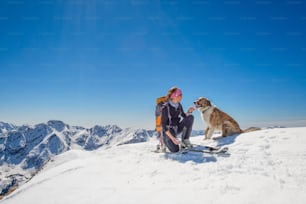 Girl ski touring with his dog at the top of the mountain
