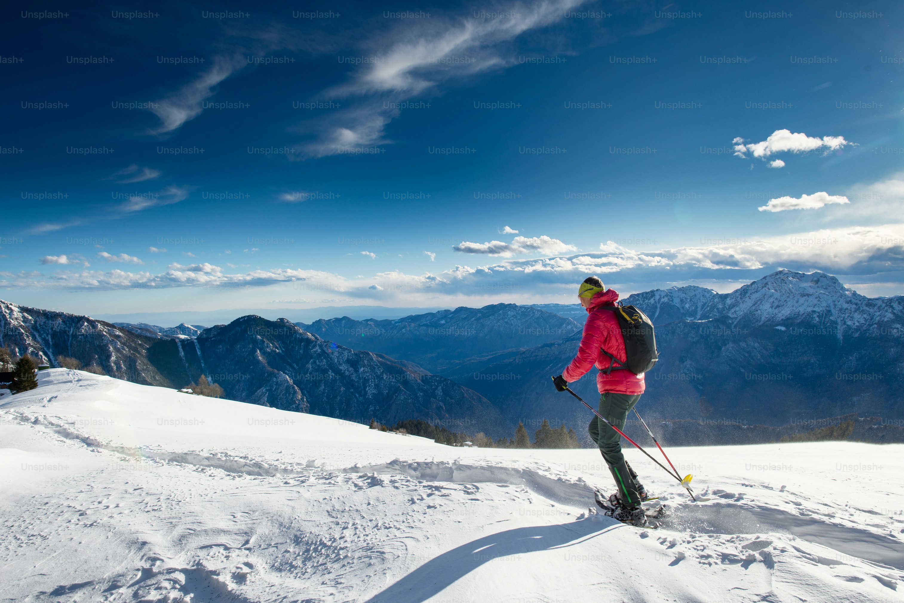 The man in snowshoes and with trekking poles In the high mountains in