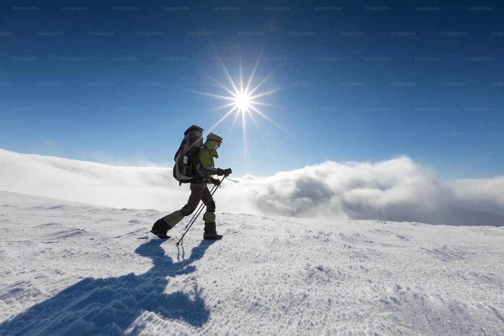 Backpacker woman is walking in winter mountains on sunny day