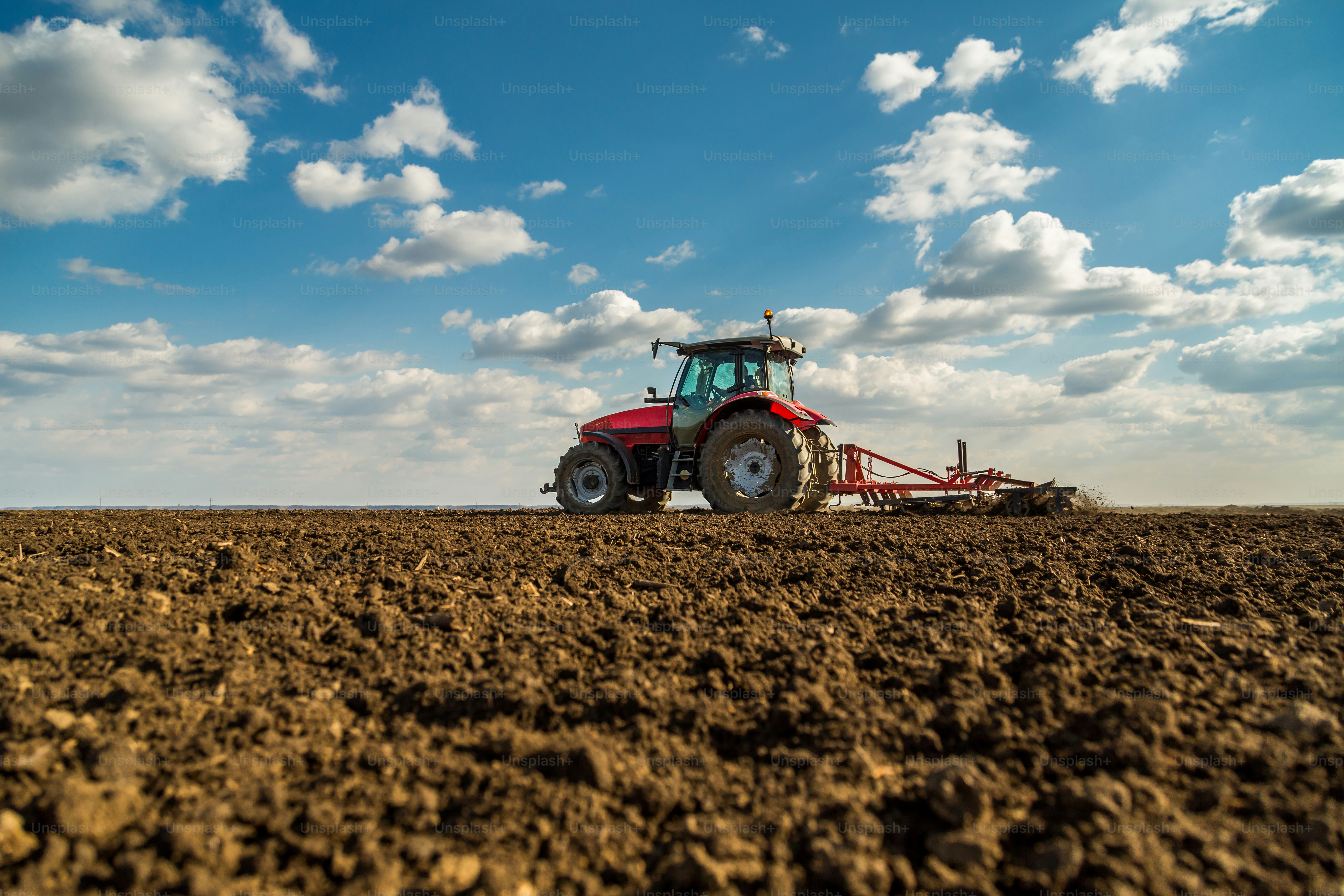 Agriculteur dans un tracteur préparant la terre avec un cultivateur de lit de semence