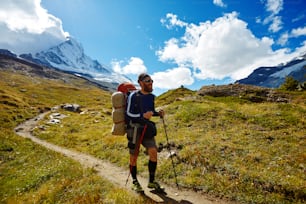 hiker with backpack on the trail in the Apls mountains. Trek near Matterhorn mount