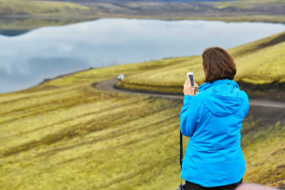 woman hiker photographer taking picture on the lake background in Iceland