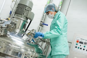 scientist in blue lab suit working with steel chromed tank with engine