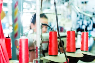 Bobine di una macchina da cucire industriale in una fabbrica, sullo sfondo che sveglia una sarta