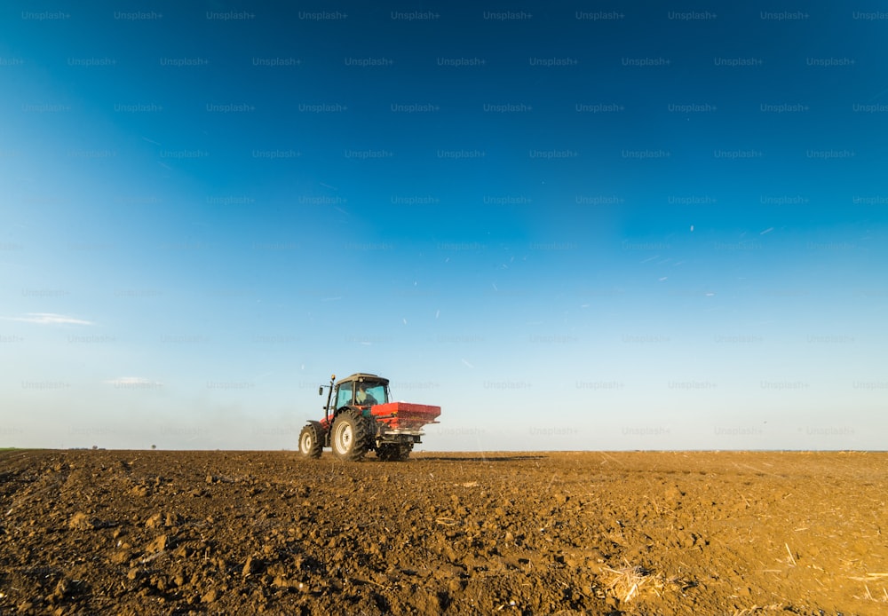 Tractor spreading artificial fertilizers  in field