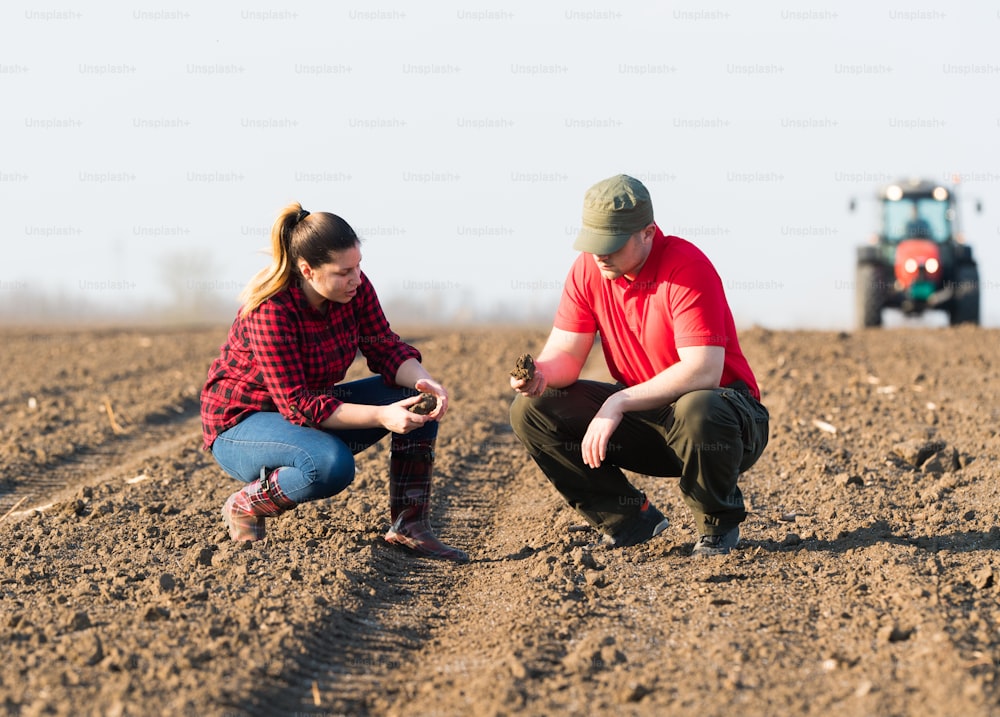De jeunes agriculteurs examinent la terre pendant que le tracteur laboure un champ