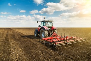 Agricultor en tractor preparando la tierra con cultivador de semillero